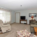 A cozy living room with a sofa, armchair, and television.