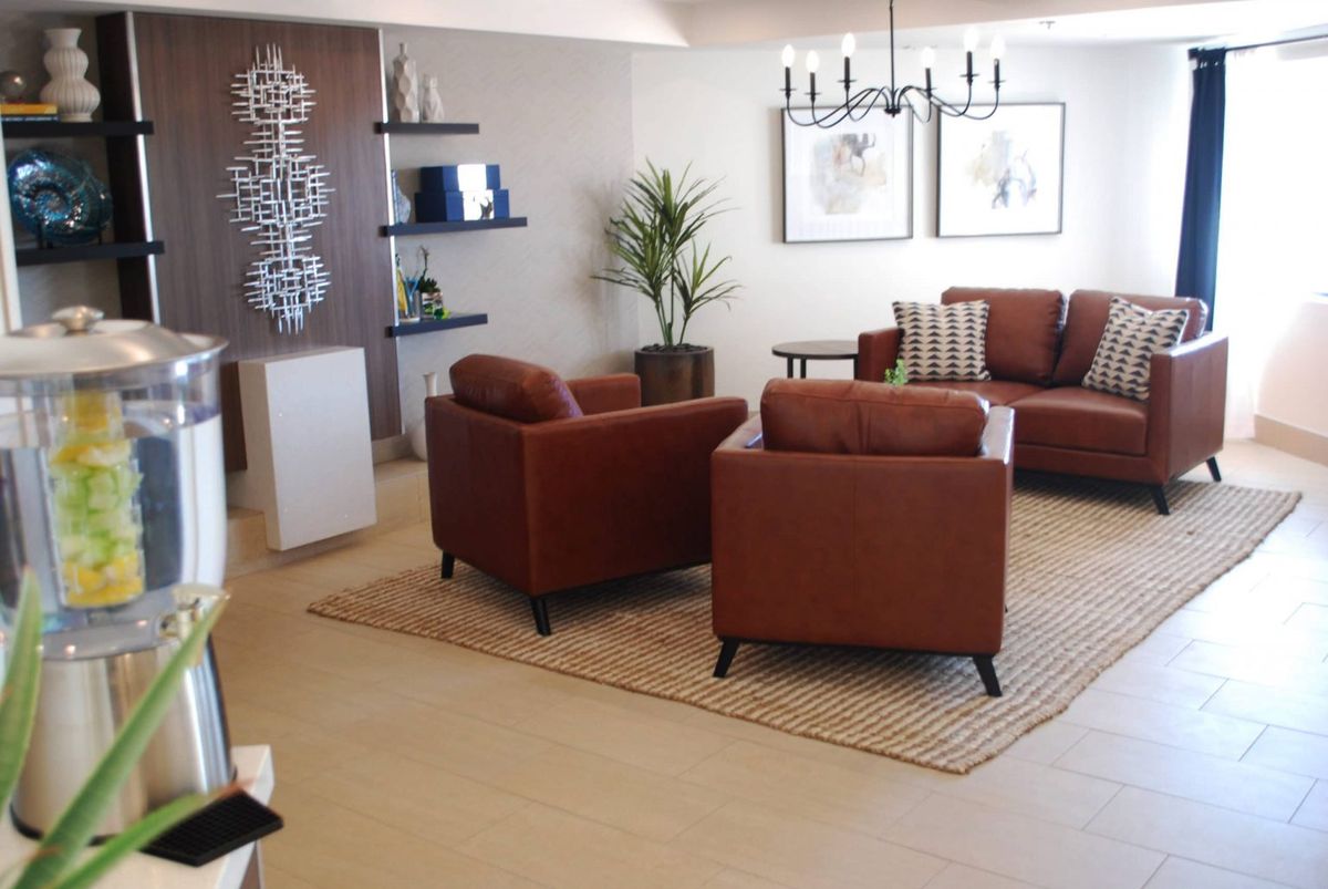 A modern living room featuring brown leather armchairs and a sofa, complemented by a stylish rug and decorative elements.