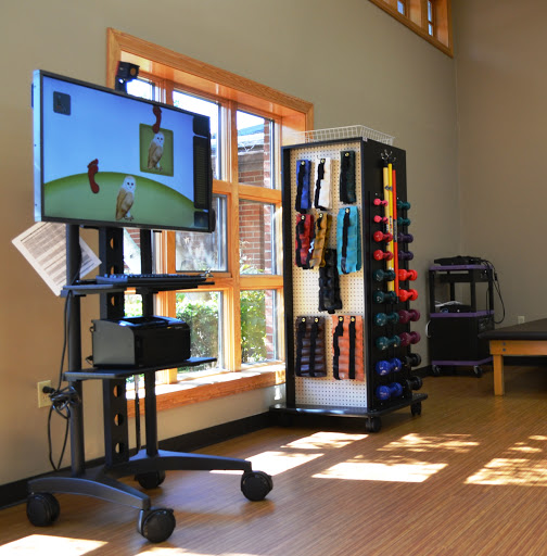 A rehabilitation space featuring interactive therapy equipment and various exercise tools for fitness and wellness.