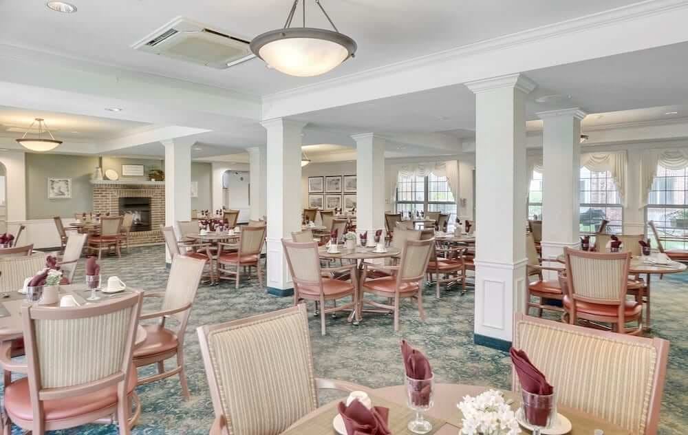 An elegantly designed dining area with neatly arranged tables and chairs, featuring soft lighting and spacious seating.