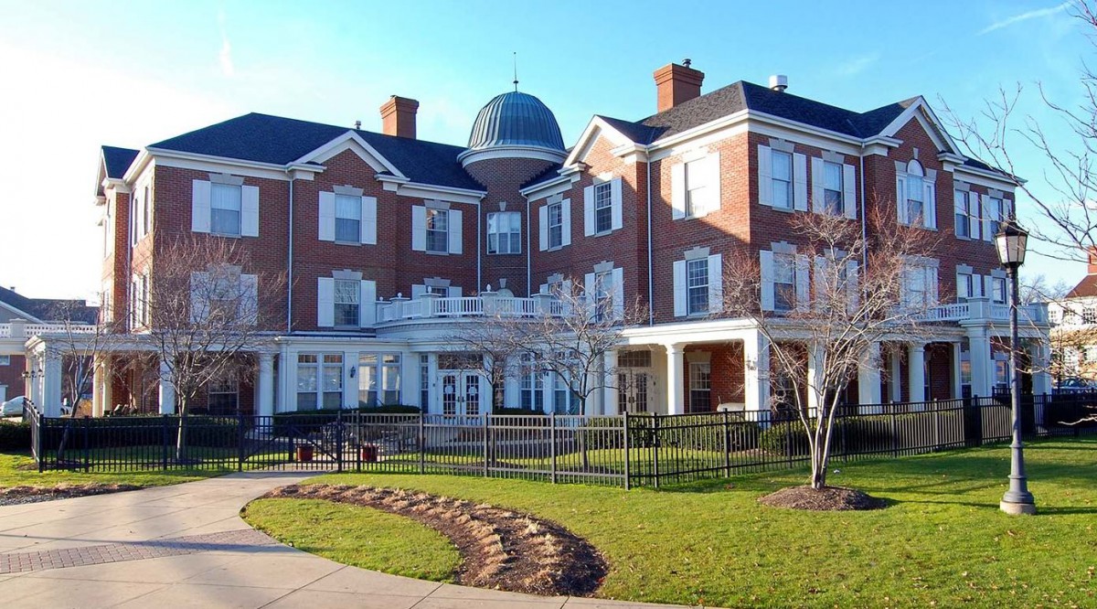 A symmetrical, historic brick building with a dome, surrounded by well-maintained landscaping.