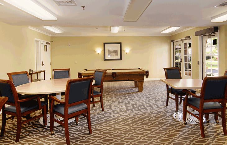 A game room featuring a pool table and several seating areas.