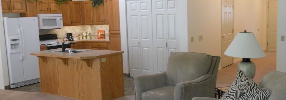 A cozy living room corner featuring a plush armchair, a kitchen counter, and white closet doors.