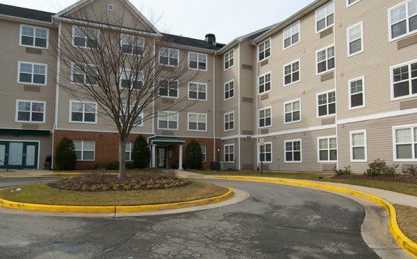 A multi-story residential apartment building with a parking area in front.