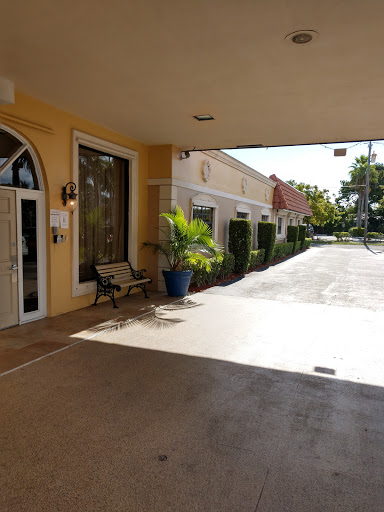 A sunny entrance to a commercial building featuring a walkway and greenery.