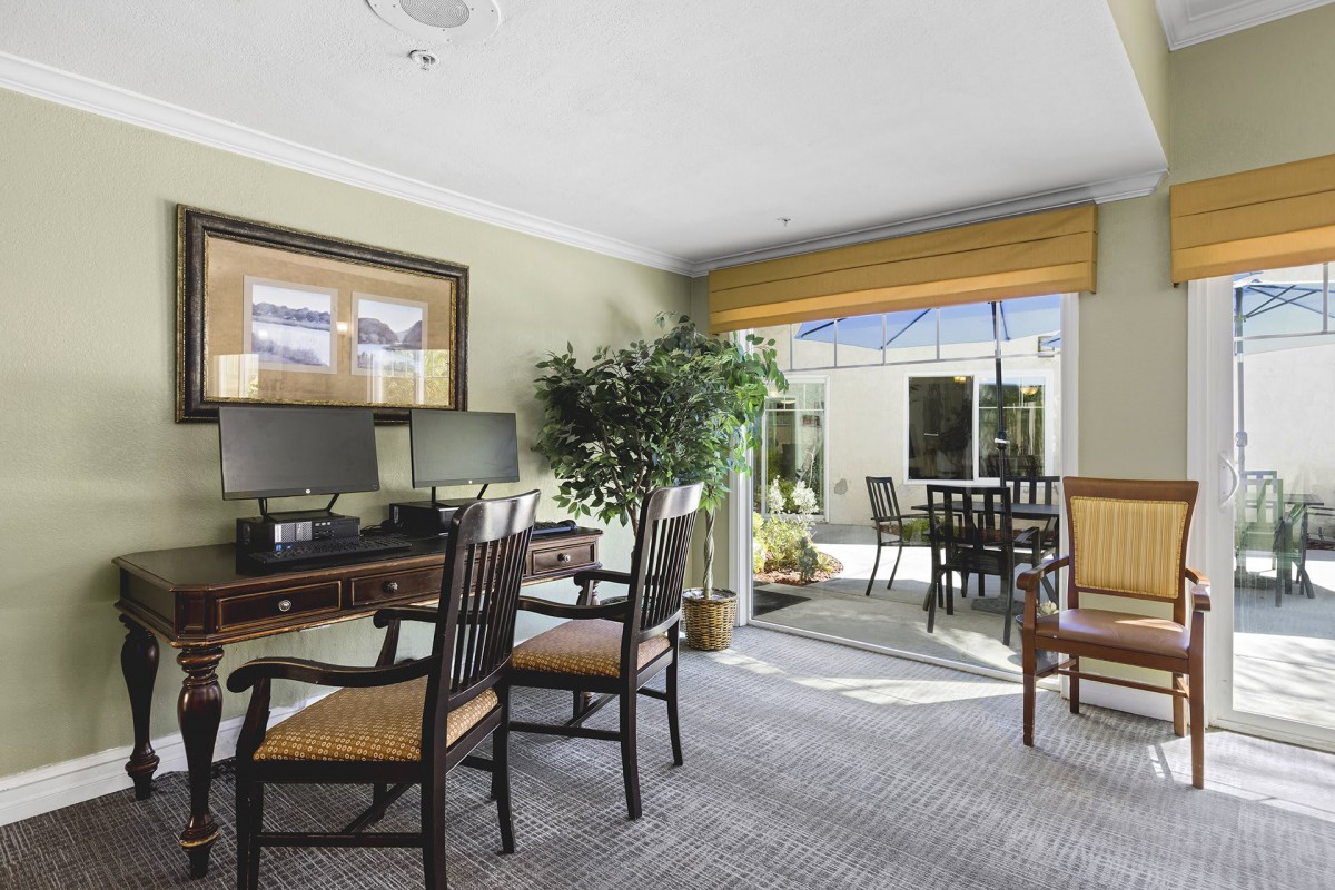 A well-lit office interior with desks, chairs, and a view of the outside patio.