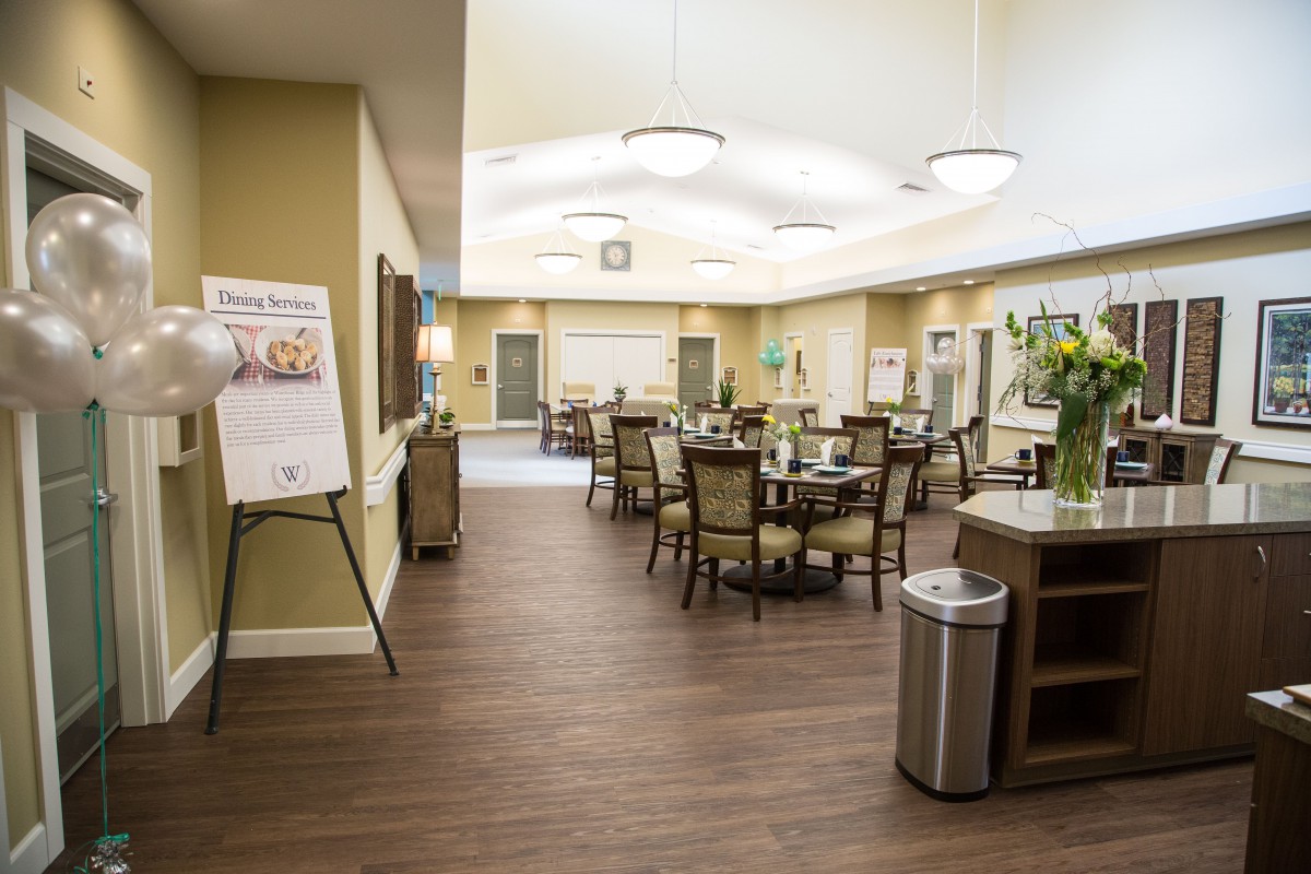 A spacious and elegantly designed dining area with neatly arranged tables and chairs, featuring stylish lighting and wood flooring.