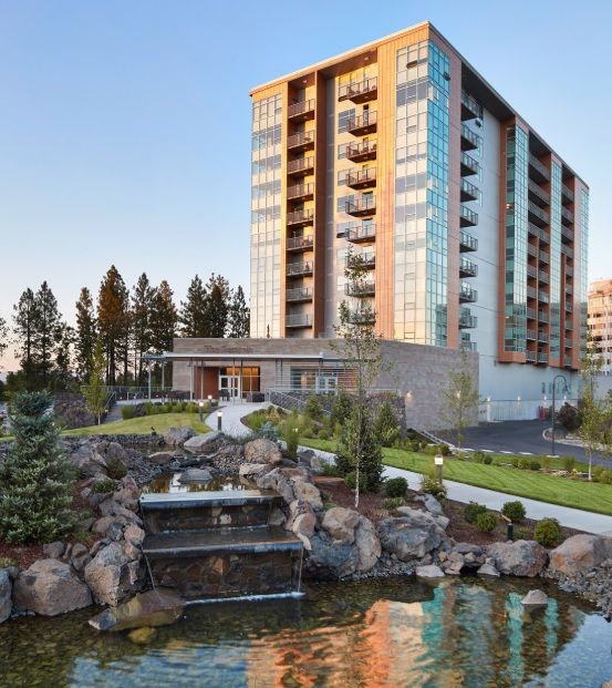 A modern high-rise apartment building with landscaped gardens and a cascading water feature.