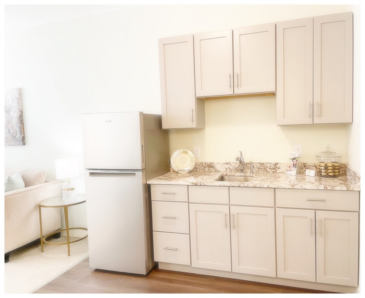A modern kitchen with light-colored cabinets, a refrigerator, and a sink.