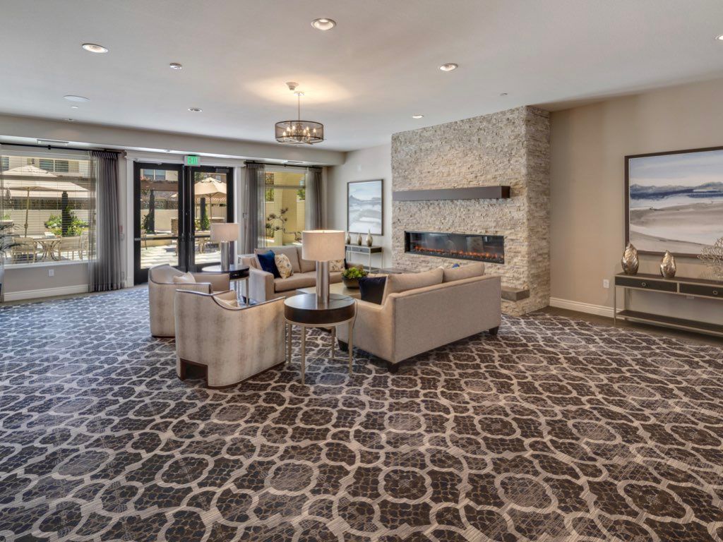 A modern living room with stylish furniture and a patterned carpet, featuring a fireplace and elegant decor.