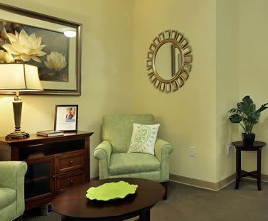 Cozy living room with a green armchair, decorative mirror, and warm lighting.