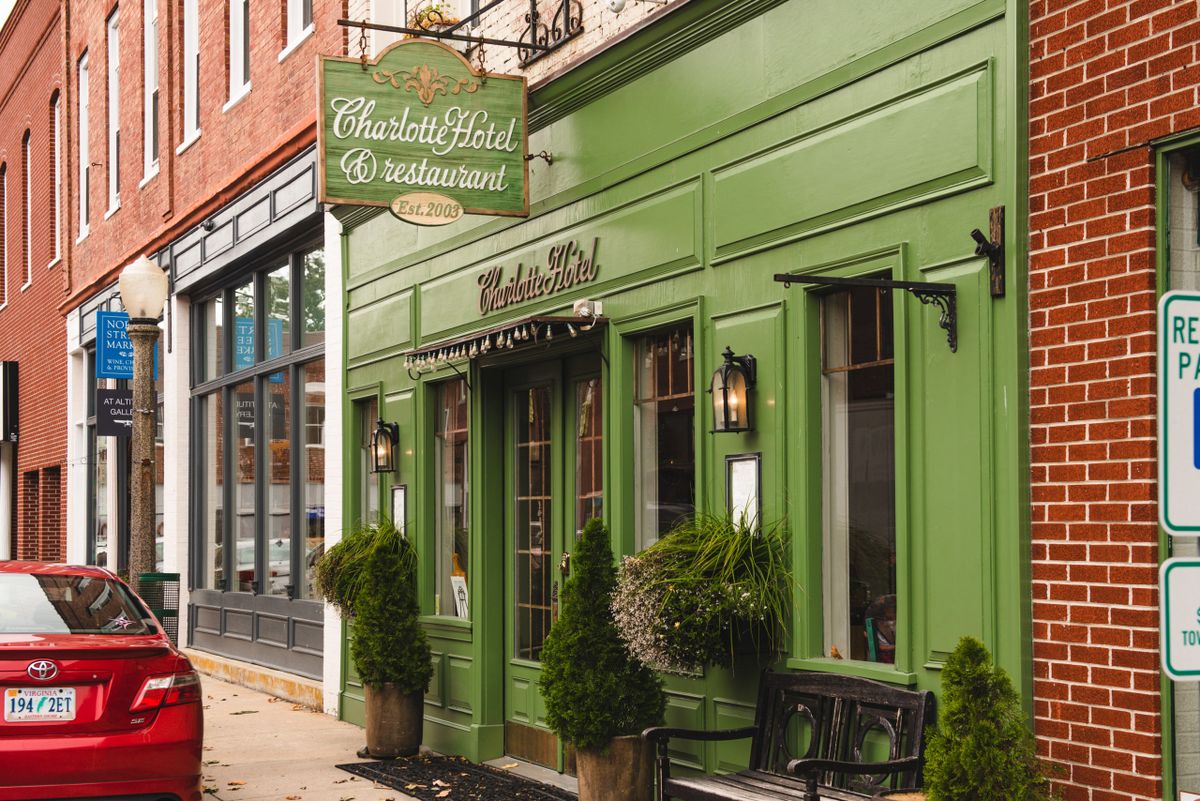 A quaint restaurant with a green facade and decorative plants at the entrance.