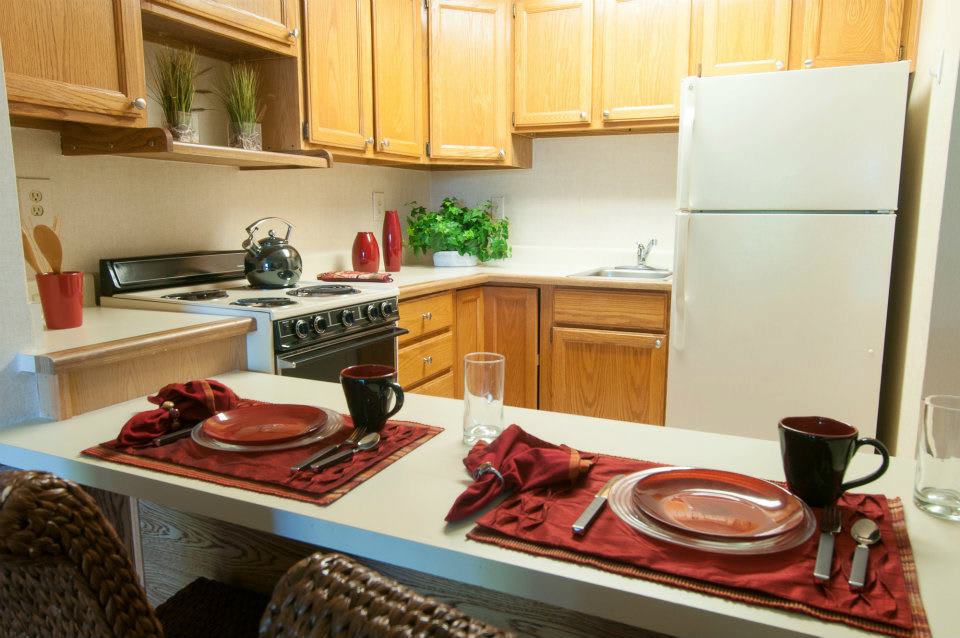 A cozy kitchen with a neatly set dining area, featuring wooden cabinets and modern appliances.
