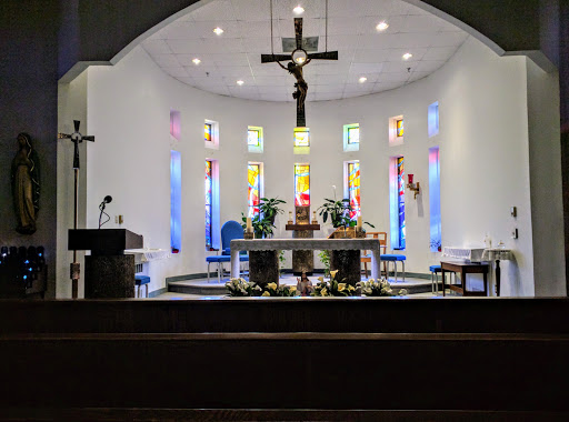 A view of the altar in a church adorned with colorful stained glass windows.