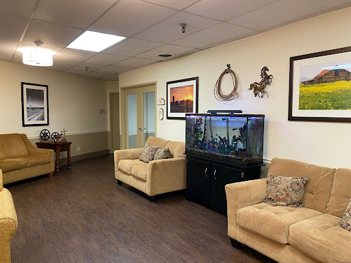 A cozy waiting area featuring soft sofas, an aquarium, and decorative photos on the walls.