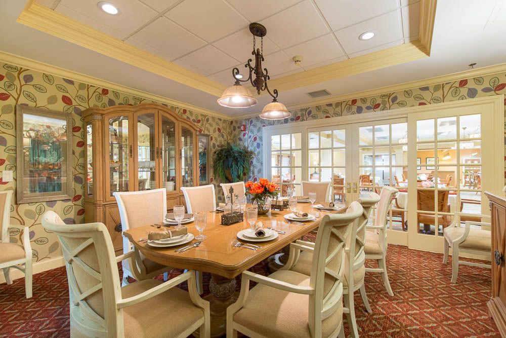 An elegantly furnished dining room with a large table, set for a meal, under a decorative chandelier.