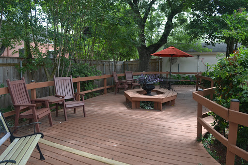 A cozy outdoor deck featuring a fire pit and comfortable seating, surrounded by lush greenery.