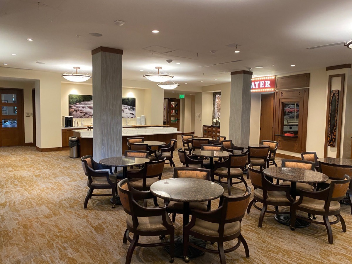 An indoor dining area with multiple tables and chairs, featuring a service counter in the background.