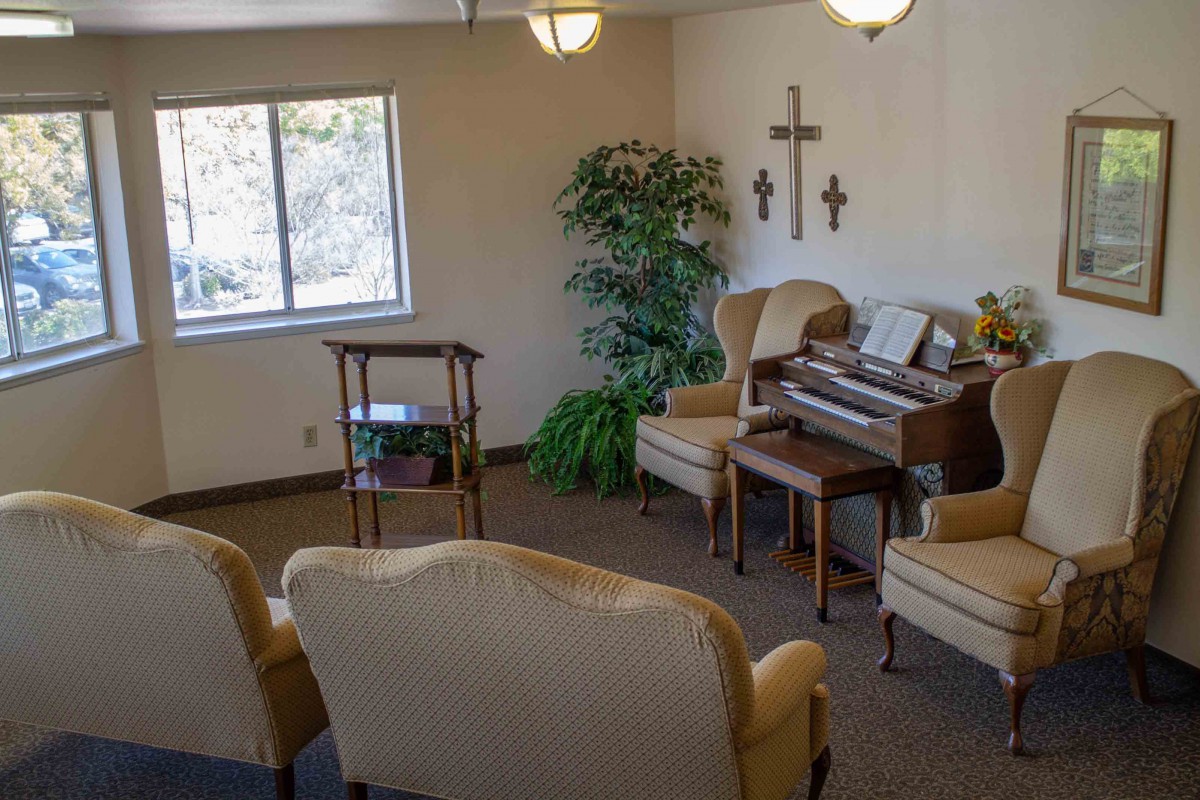A cozy room with comfortable seating, a piano, and decorative crosses on the wall.