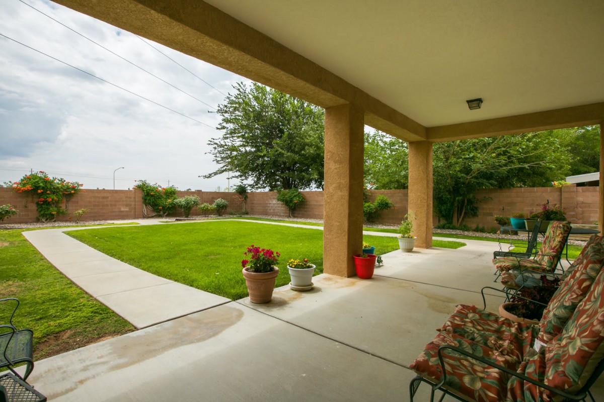 A spacious patio overlooks a well-manicured lawn and garden, featuring outdoor seating and decorative plants.