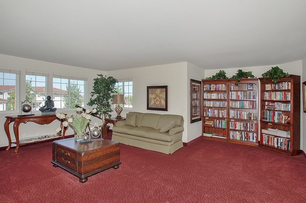 A cozy living room with a sofa, bookshelf, and indoor plants.