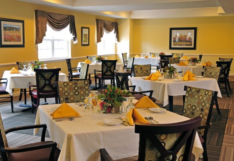 A well-decorated restaurant interior with neatly arranged tables featuring yellow napkins.