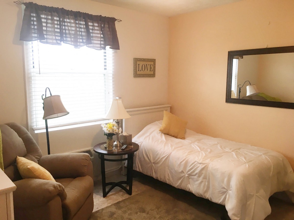 A cozy bedroom with a single bed, armchair, and decorative elements.