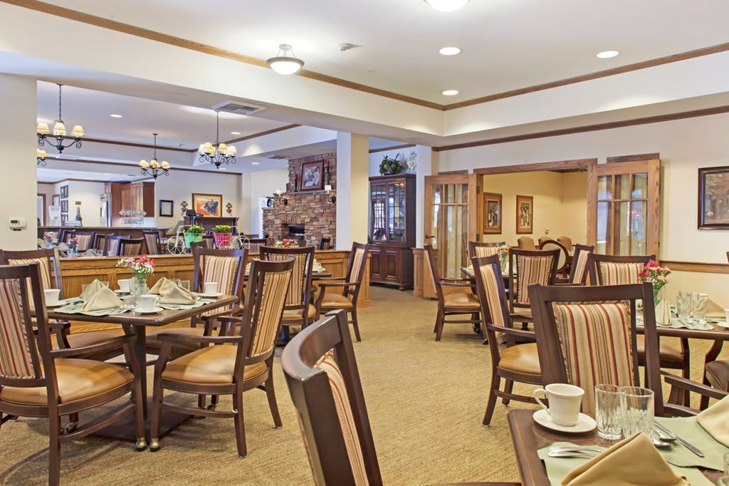 A cozy dining area with neatly arranged tables and chairs, softly lit by ceiling lights.