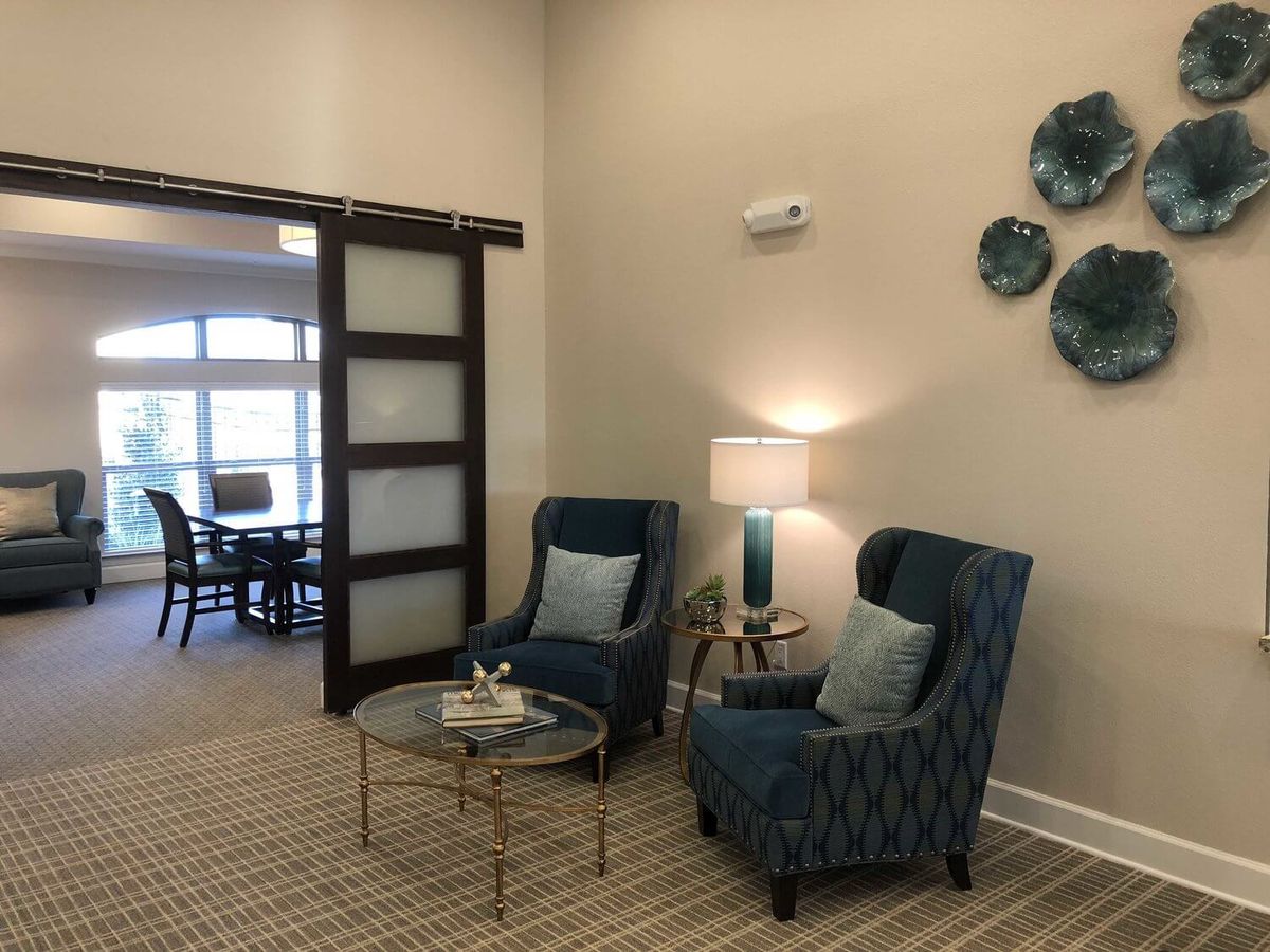 A cozy seating area with two armchairs and a coffee table, illuminated by a lamp.