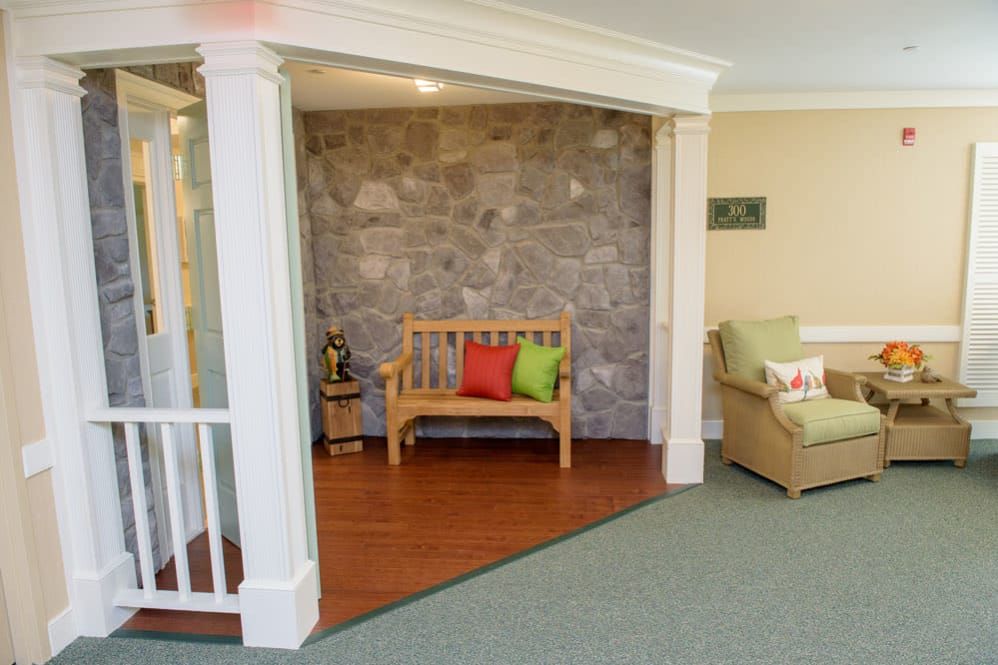 Cozy seating area with a wooden bench and colorful pillows against a rustic stone wall.