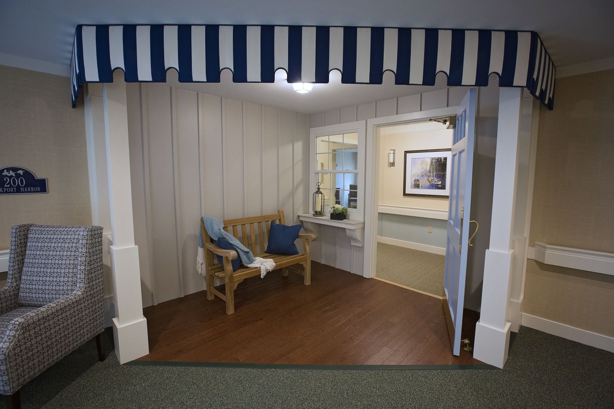 A cozy indoor seating area featuring a wooden bench with blue cushions, under a striped awning.