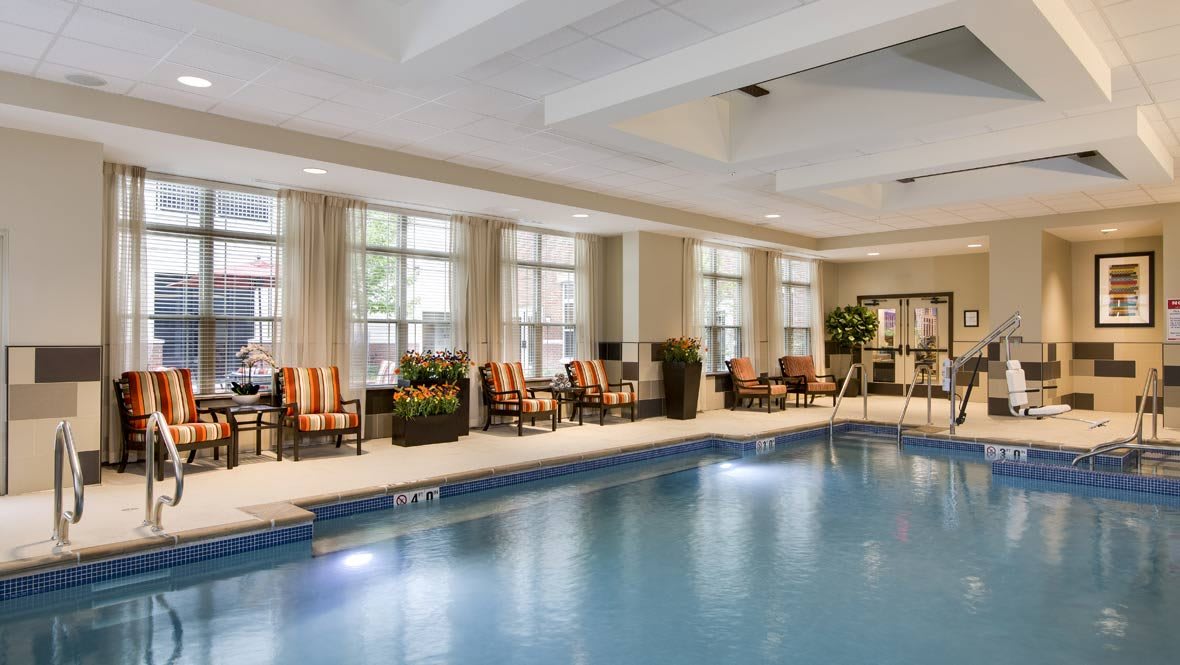 A luxurious indoor pool area featuring comfortable seating and large windows.