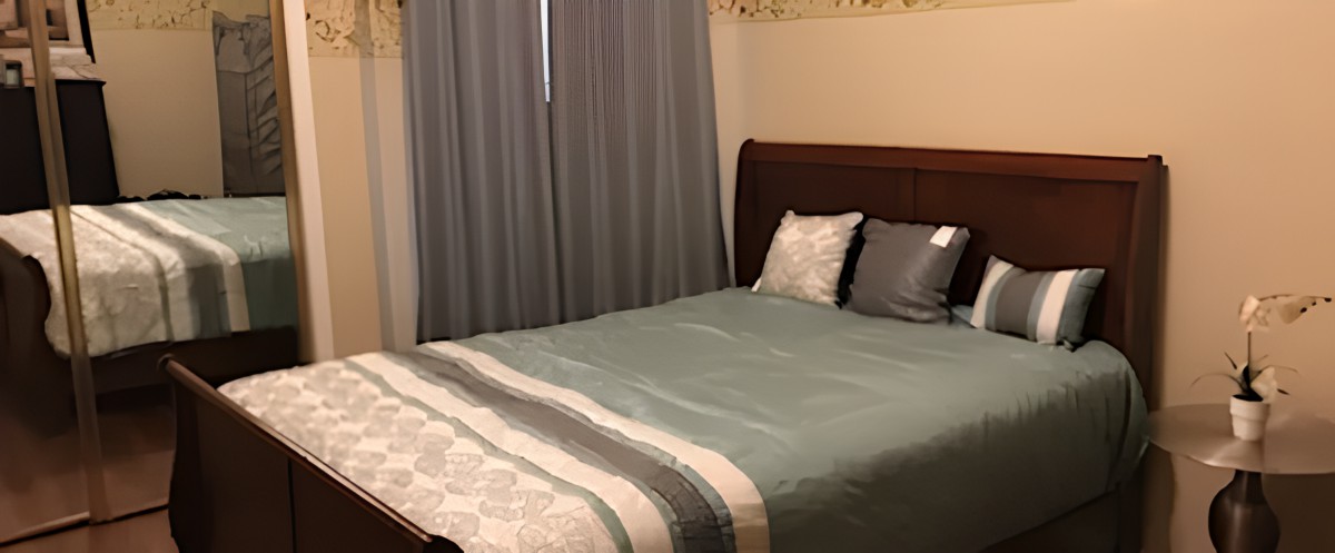 A cozy bedroom with a neatly made bed and closed curtains.