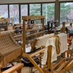 A workshop filled with weaving looms and textiles.