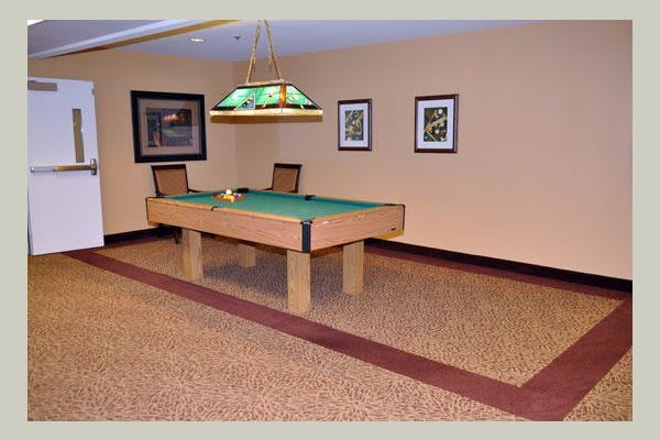A cozy game room featuring a billiards table under a hanging lamp.