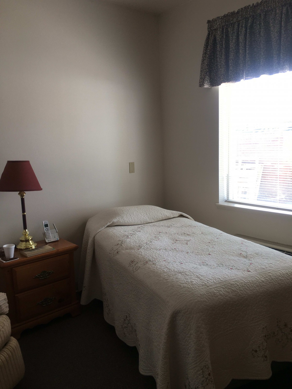 A minimalist bedroom with a single bed, nightstand, and window.