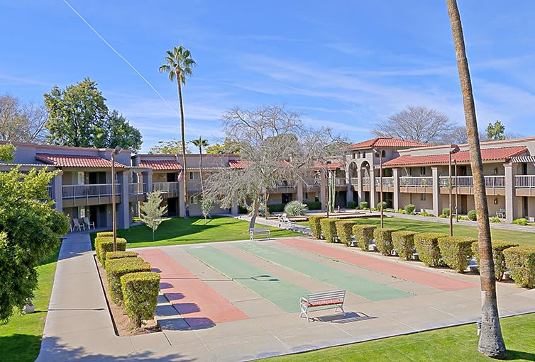 A sunny day at a courtyard of an apartment complex, featuring well-maintained landscaping and a palm tree.