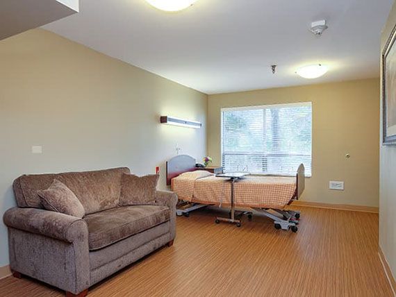 A clean and well-lit hospital room featuring a patient bed and a sofa.