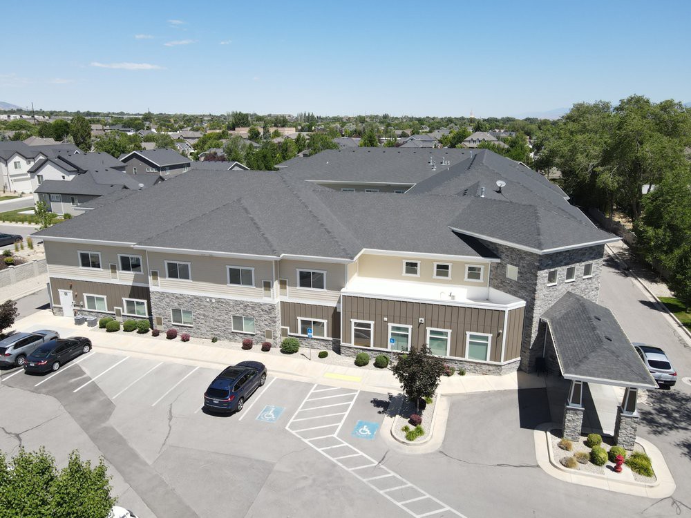 Aerial view of a large building with a parking lot and cars.