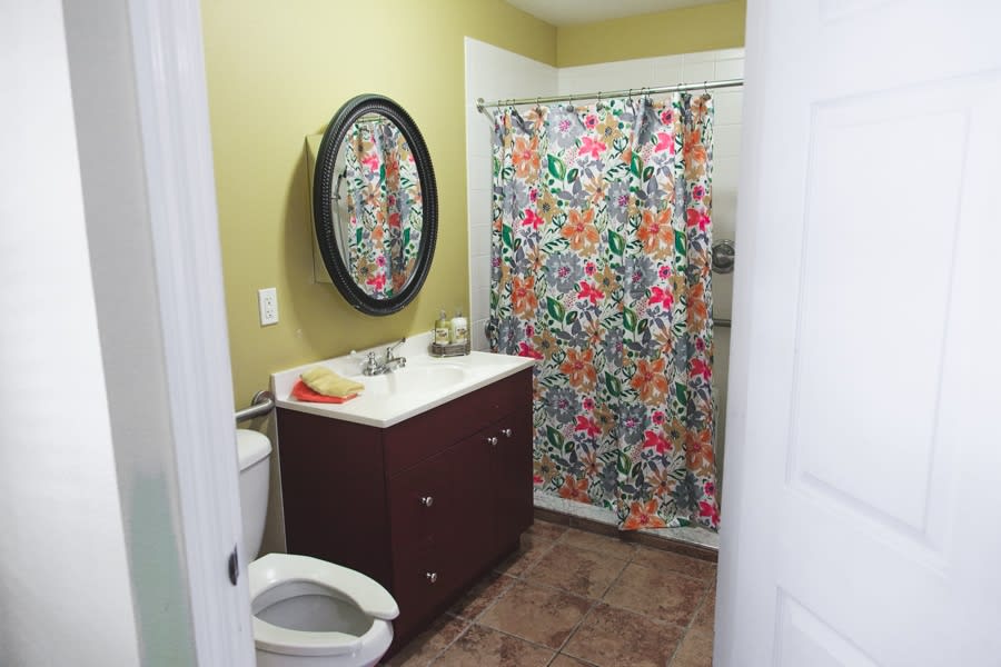 A cozy bathroom with a colorful floral shower curtain and wall mirror.