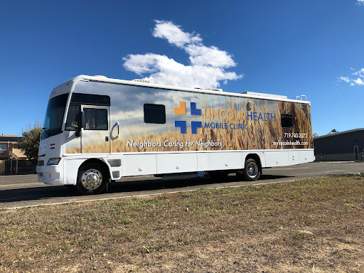 A mobile healthcare clinic parked on a roadside, featuring a design showcasing wheat fields.