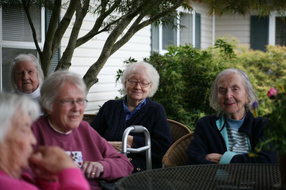 A group of elderly people sitting together outdoors, enjoying each other's company.