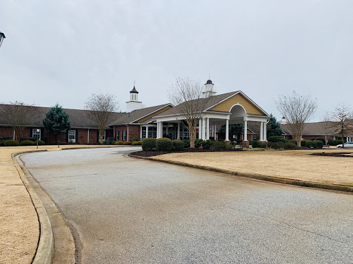 A residential building viewed from the entrance, set against a cloudy sky.