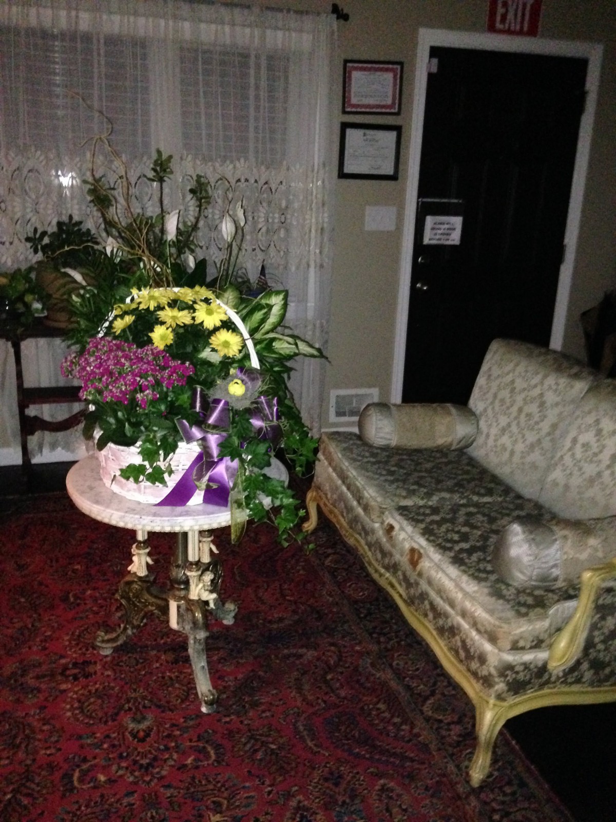 A cozy room with vintage furniture and a floral arrangement on a small table.