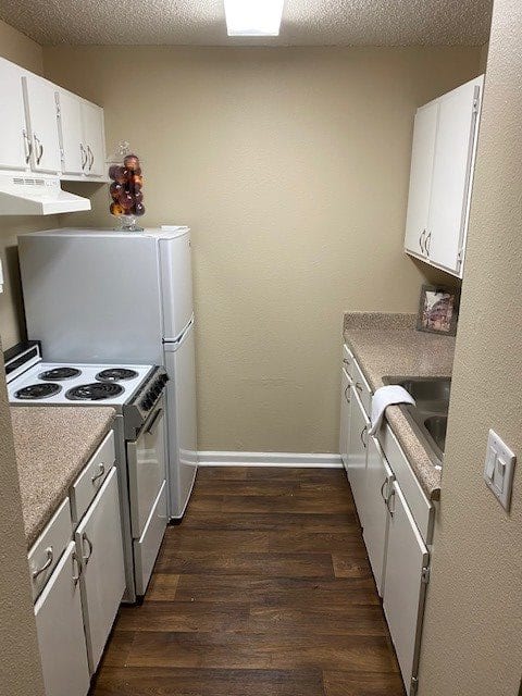 A compact apartment kitchen with white cabinets and an electric stove.