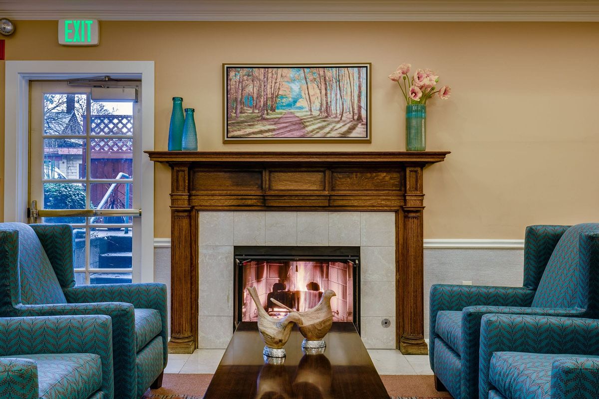 A cozy living room with a fireplace, surrounded by comfortable seating and adorned with artwork and decor.