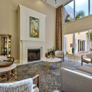 A beautifully designed modern living room with a fireplace, high ceilings, and large windows.