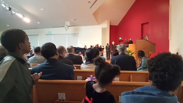 A view of a church interior during a ceremony, with an audience seated in pews.