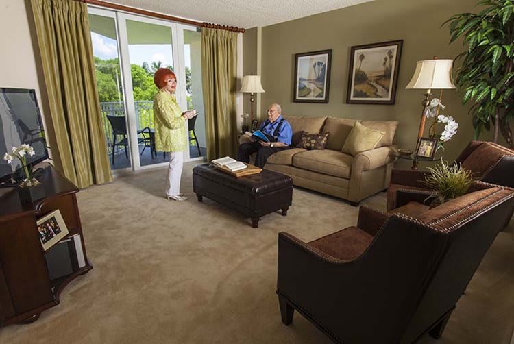 A cozy living room with two people relaxing, featuring comfortable furniture and decorative elements.