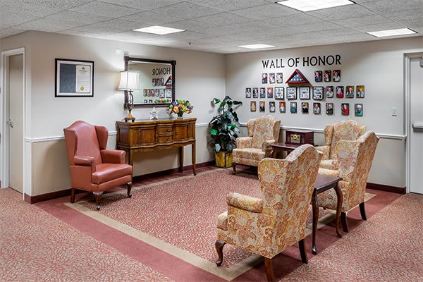 A cozy lobby area with armchairs and a 'Wall of Honor' featuring photographs.